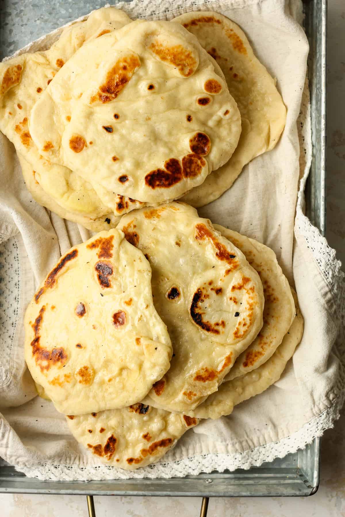A gray tray of naan on a towel.