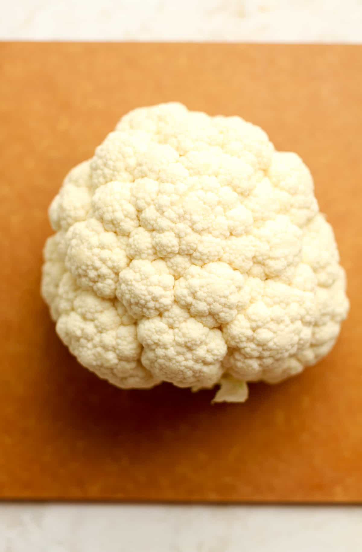 A head of cauliflower on a board.