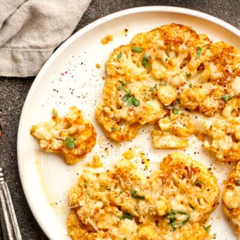 A plate of two cheesy cauliflower steaks.
