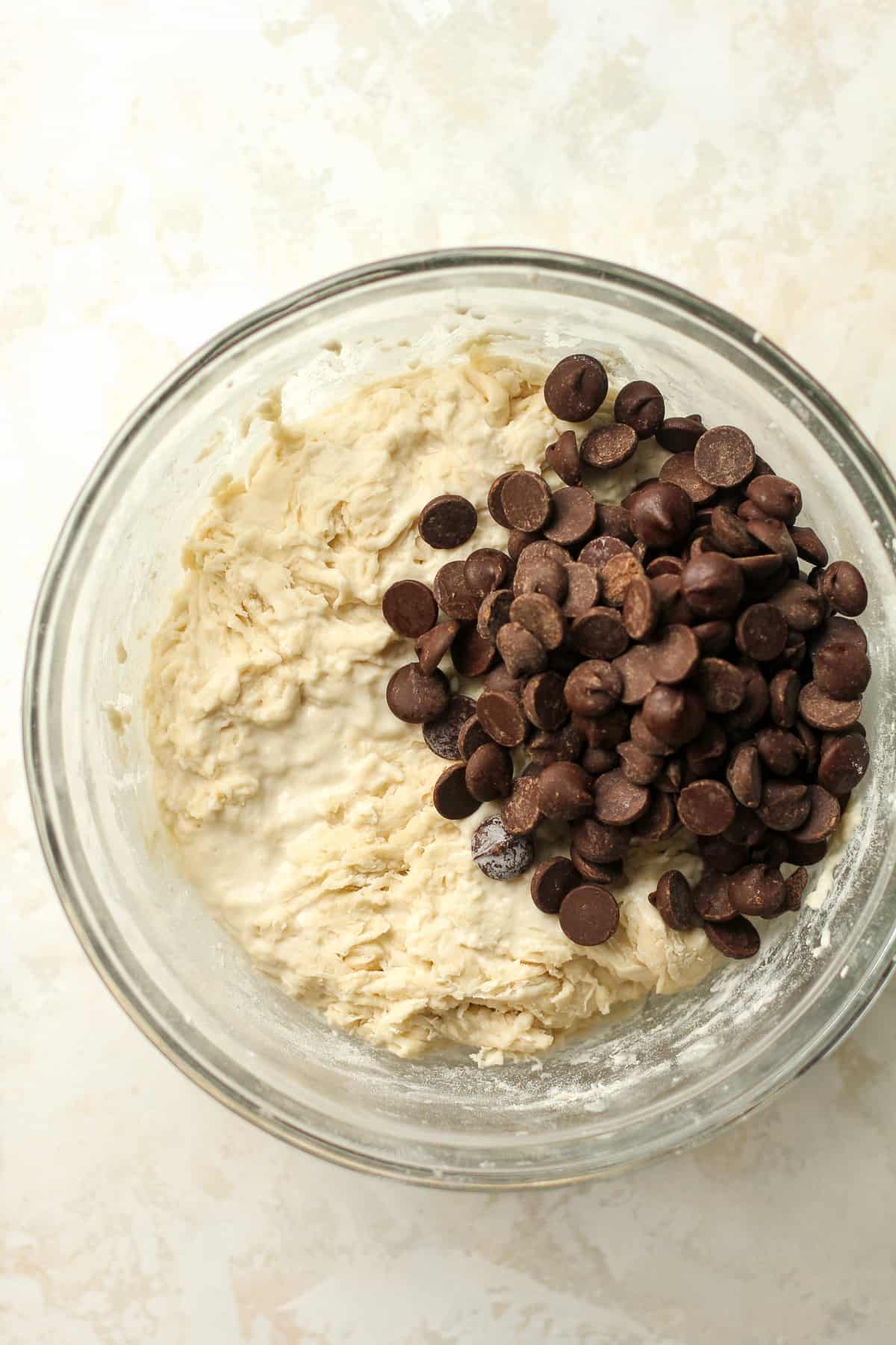 A bowl of the shaggy dough with dark chocolate chips on top.