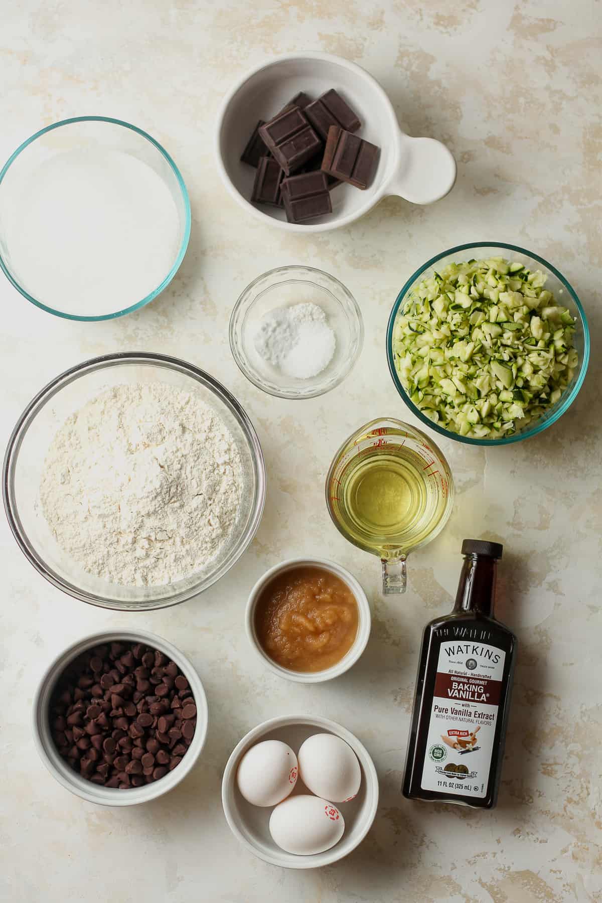 The ingredients for chocolate zucchini muffins in small bowls.