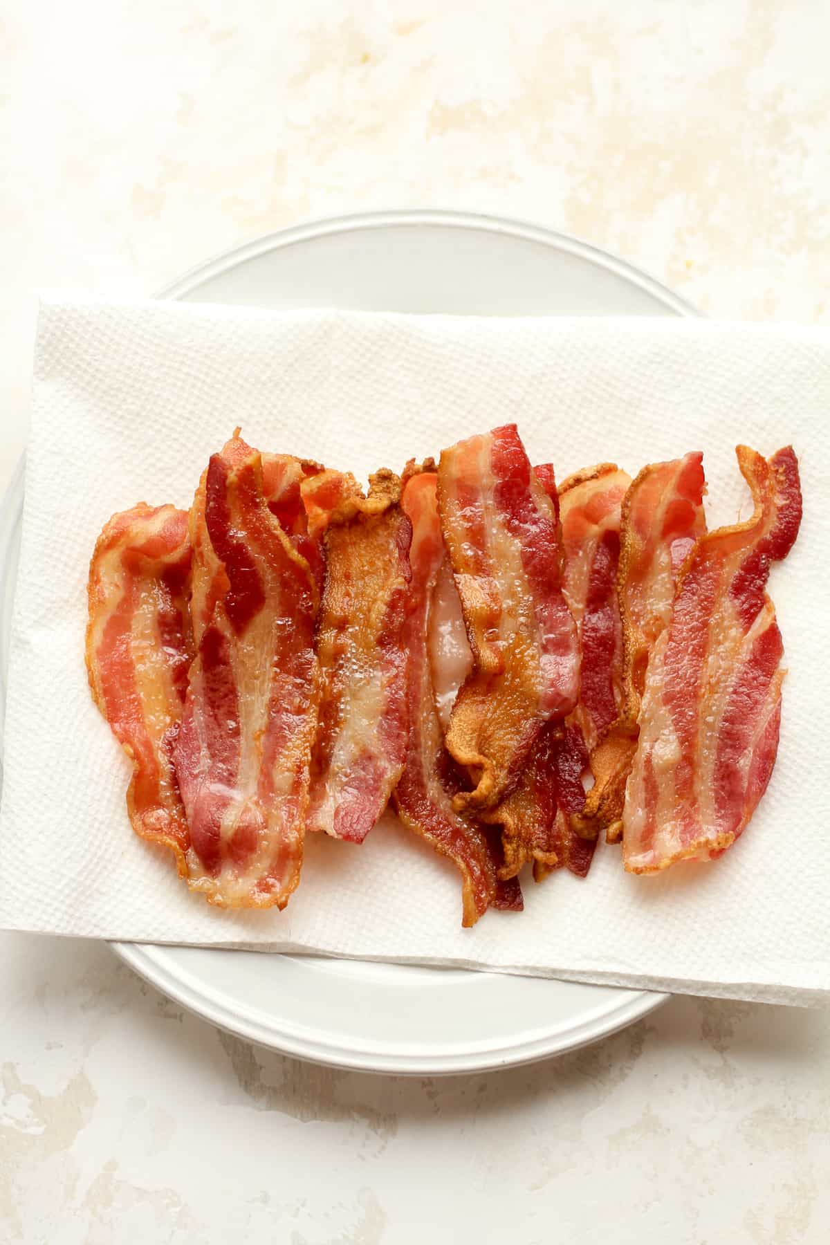 A plate of the cooked bacon on paper towel.