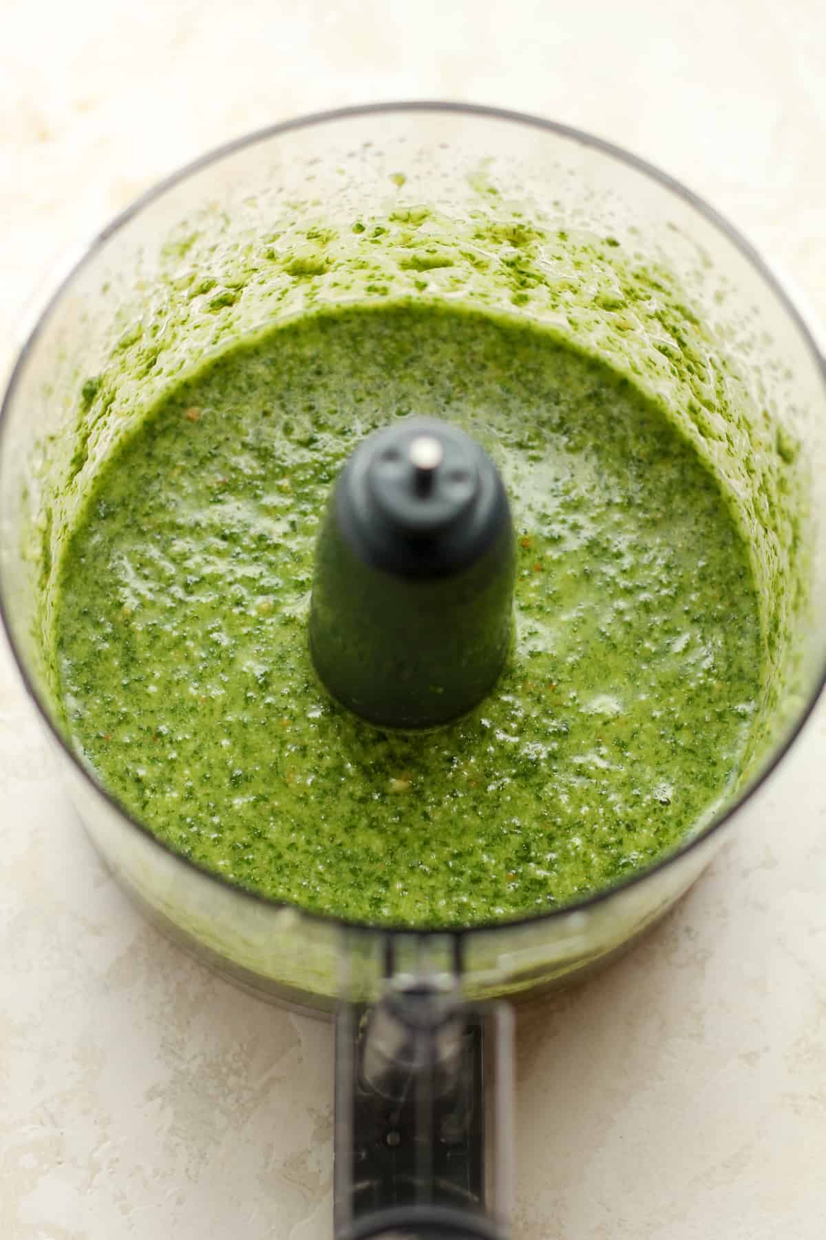 A food processor filled with fresh pesto sauce.