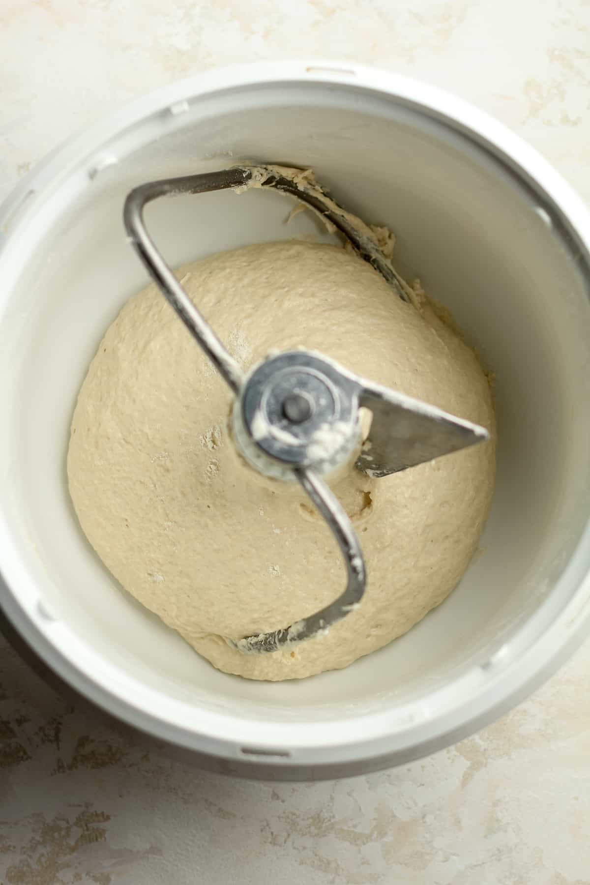 A mixer bowl with the homemade pizza dough with a dough hook.