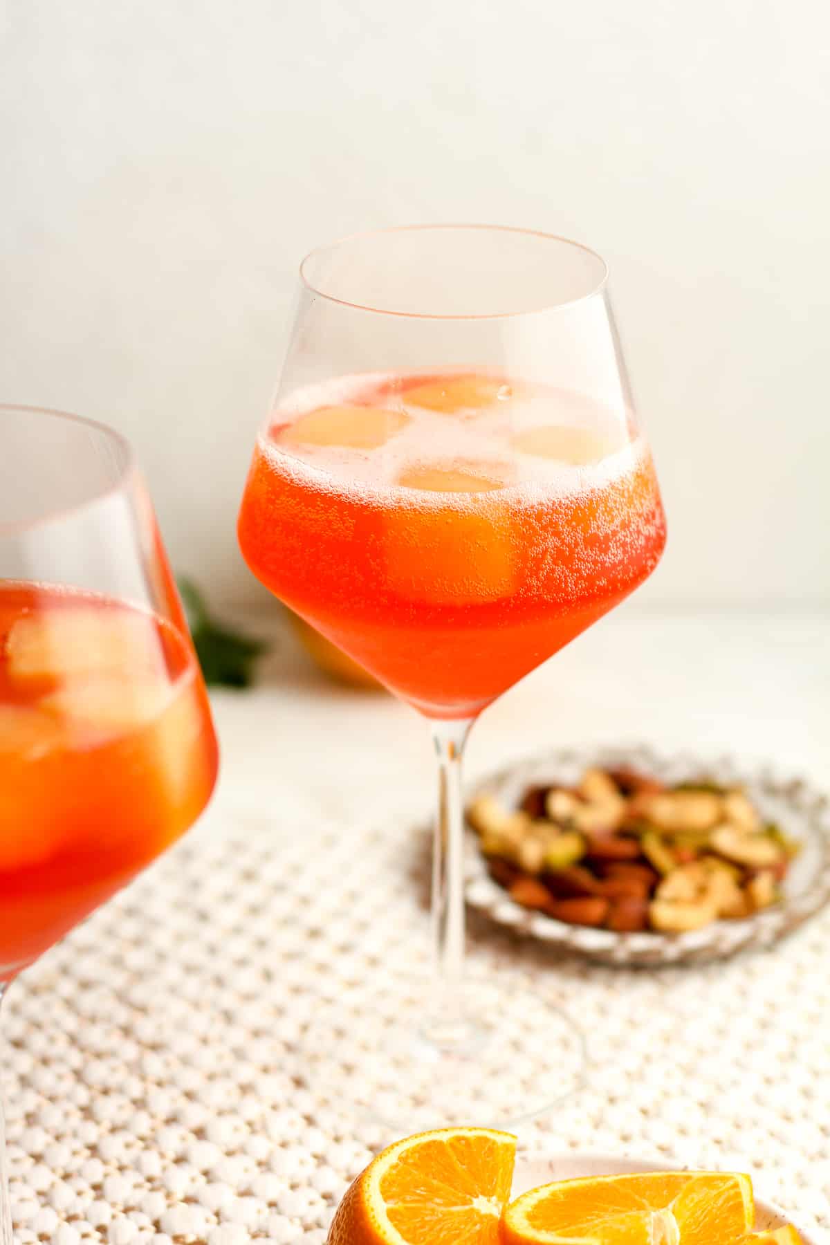Side shot of a wine glass of aperol spritz with fizz on top.
