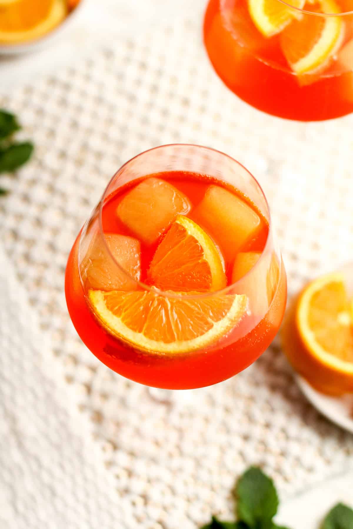 Closeup on two glasses of aperol spritz with orange cubes.