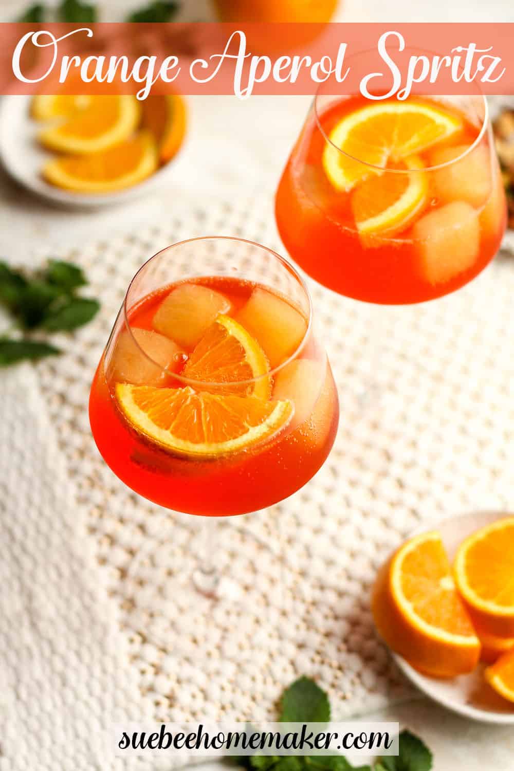 Overhead shot of two wine glasses of orange aperol spritz with orange slices.