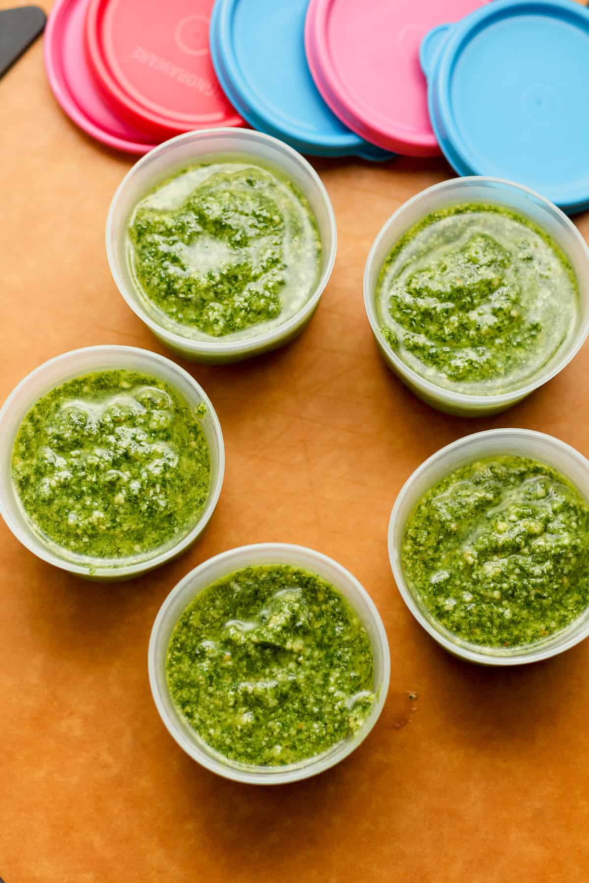 Five small containers of just made homemade pesto sauce.