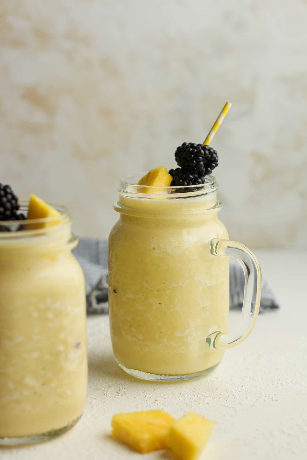 Side view of two mugs of pineapple banana smoothies.