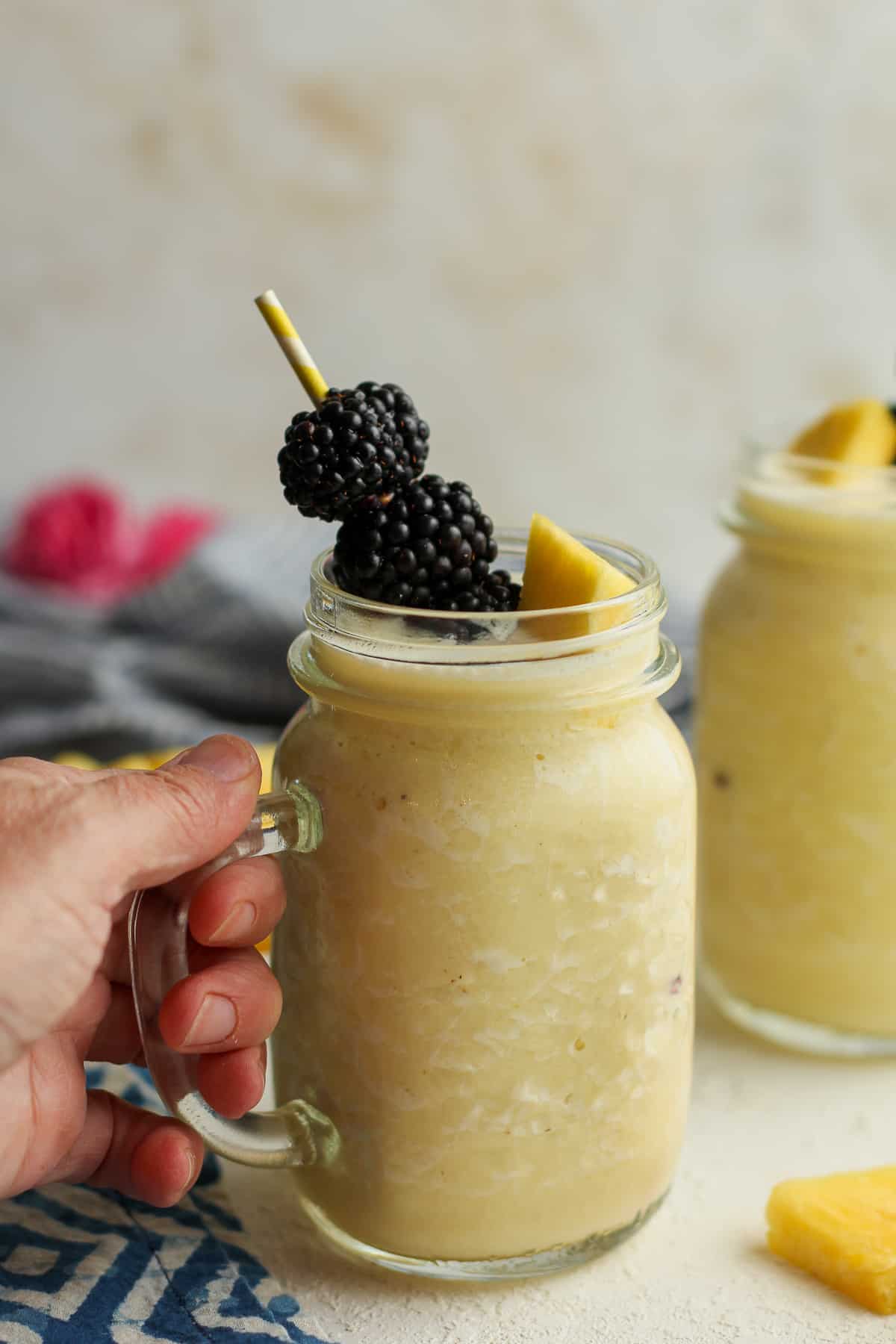 My hand on the pineapple banana smoothie with blackberry garnish.