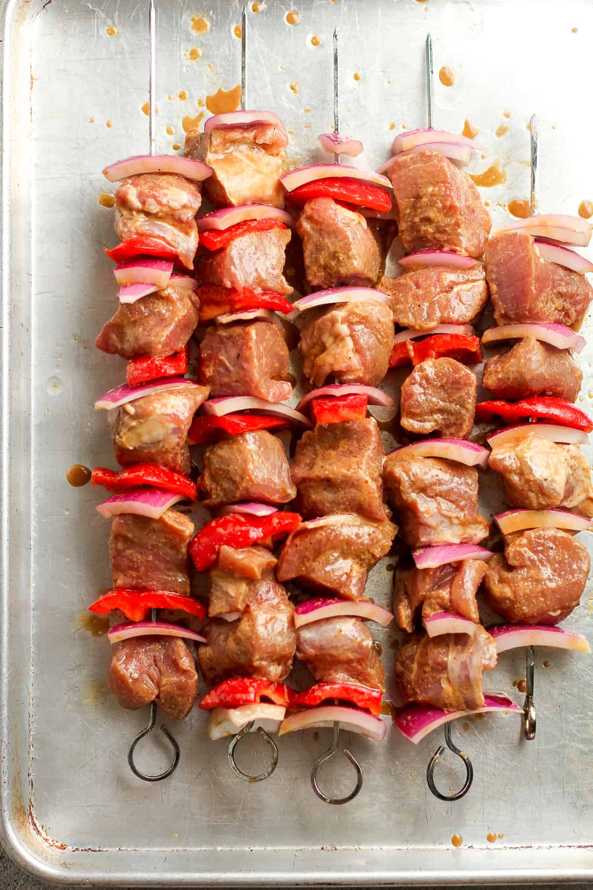 The raw kabobs before grilling on a sheet pan.