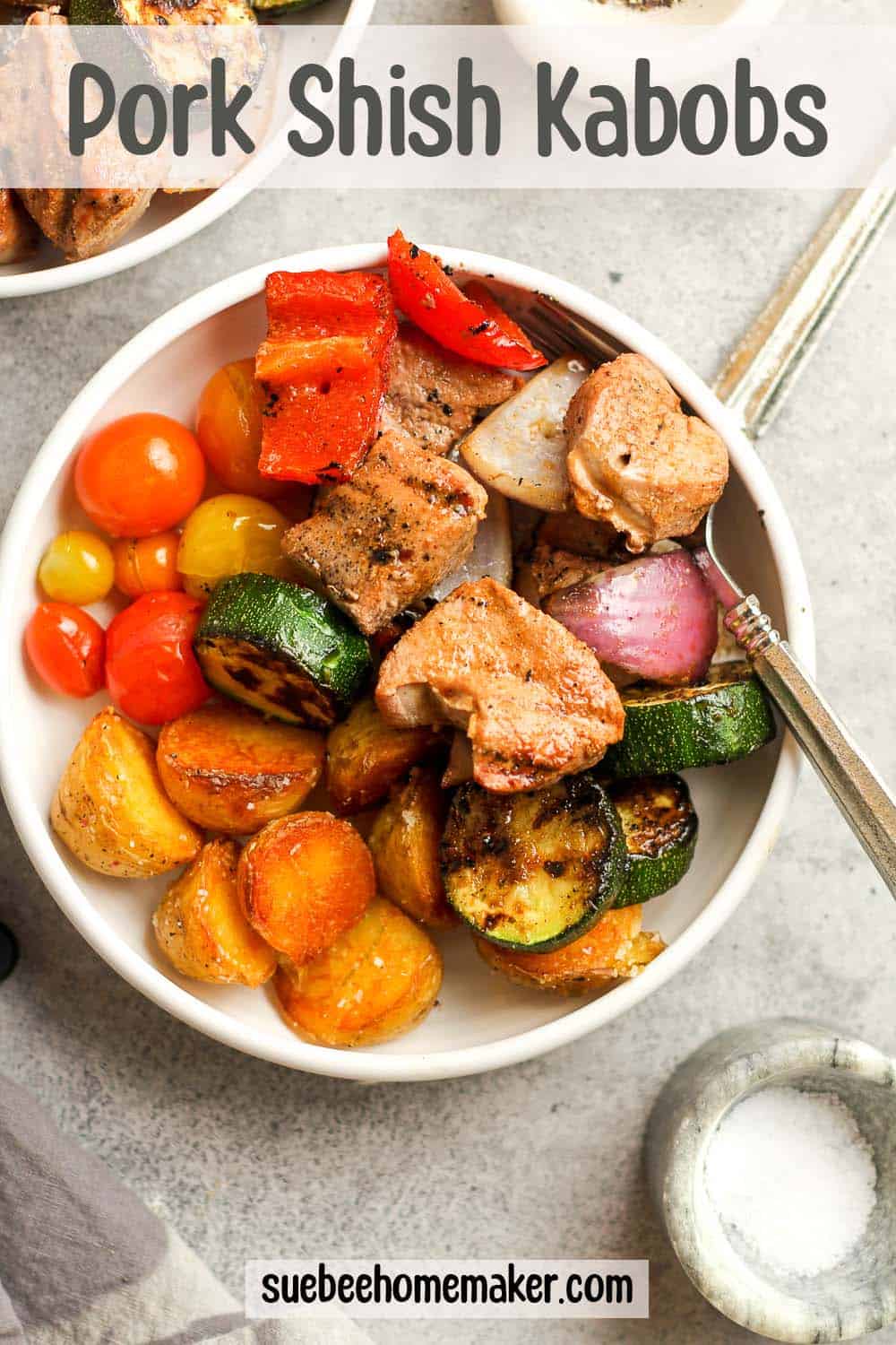 A bowl of pork shish kabobs with grilled potatoes.