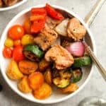 A bowl of pork kabobs with grilled potatoes with a fork.