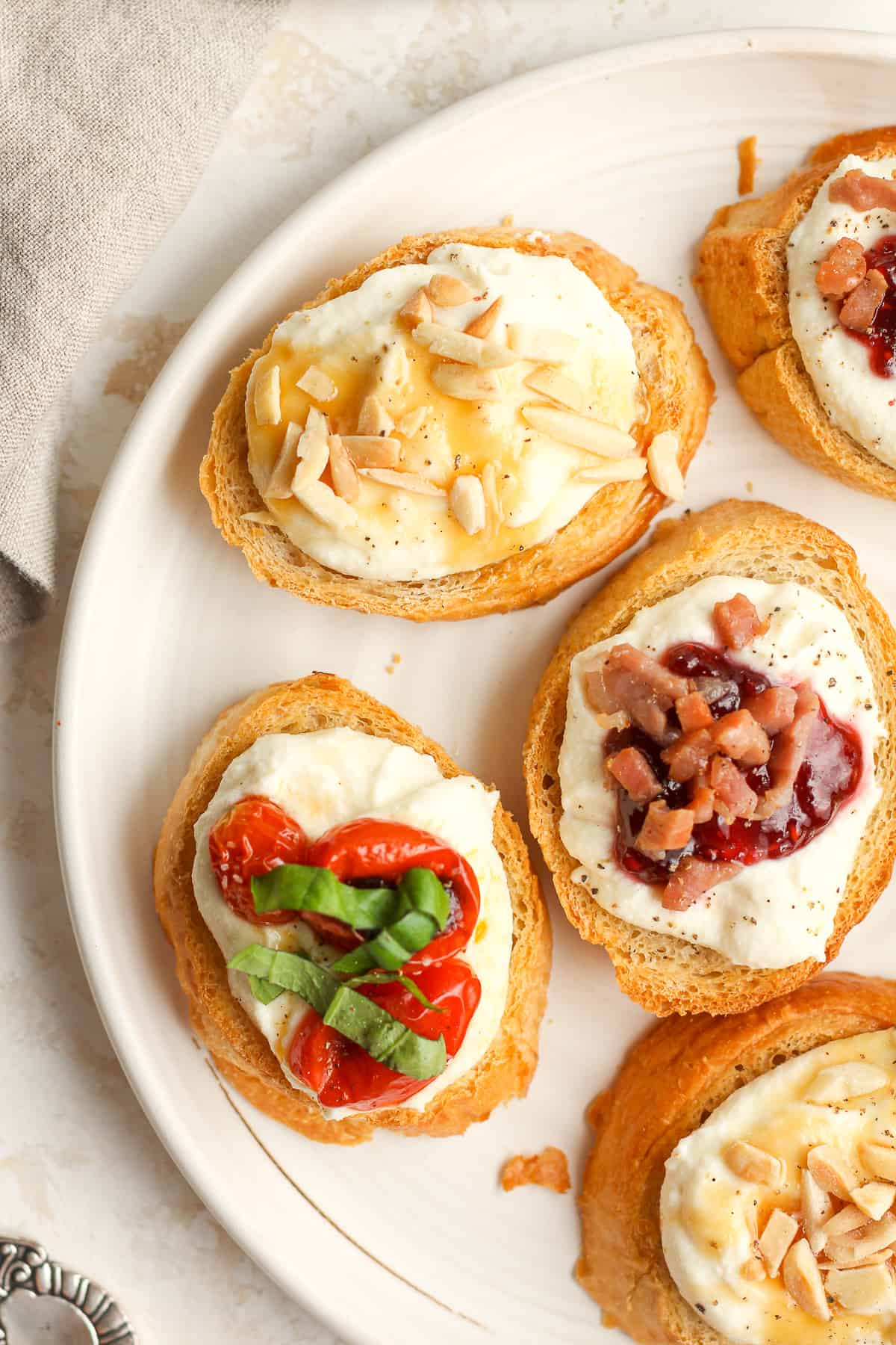 A shot of a partial plate of ricotta crostini with different toppings.