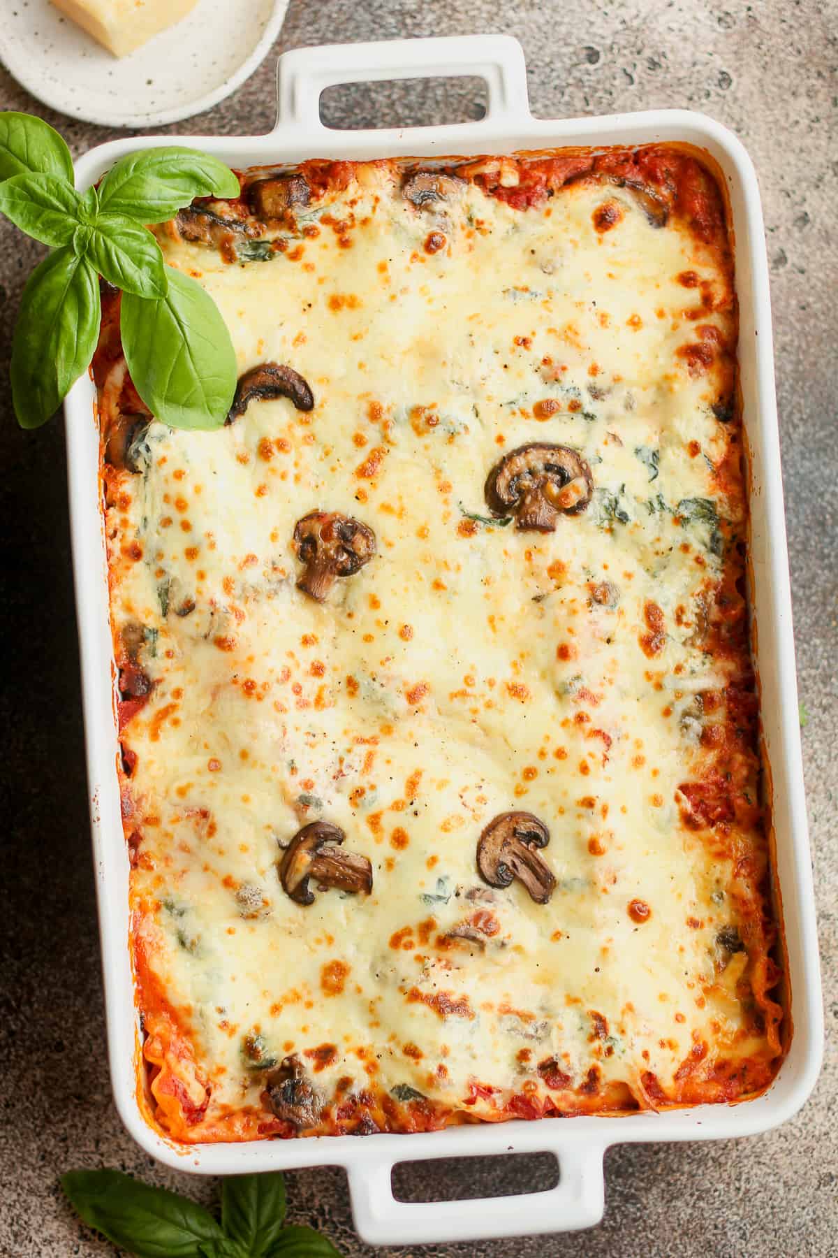 A large casserole of spinach lasagna with mushrooms.