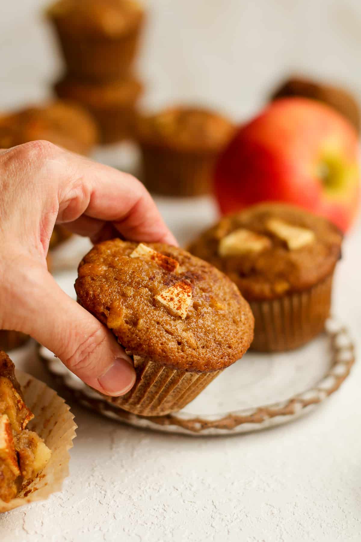 A hand reaching for a baked applesauce cinnamon muffin.