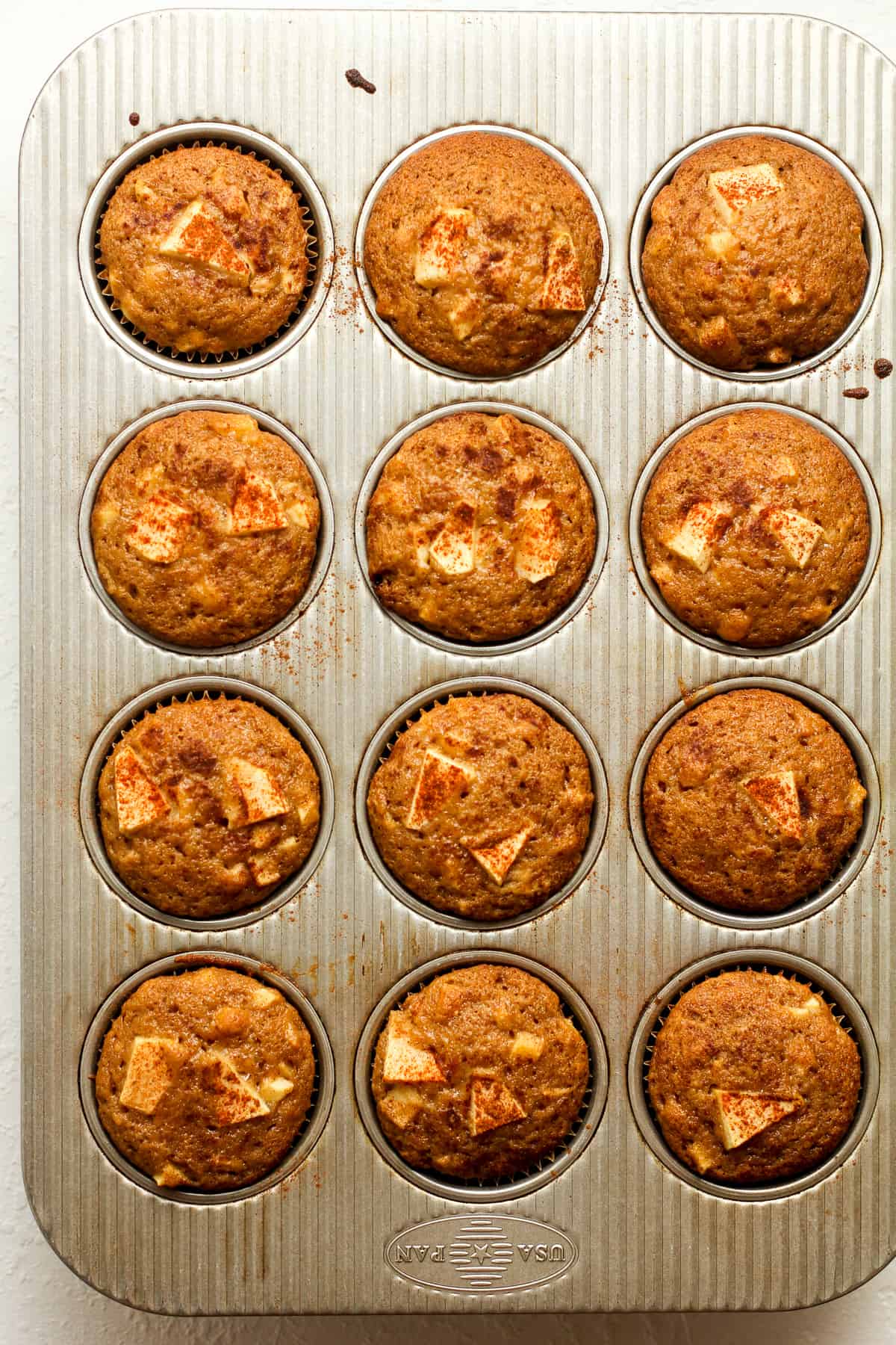 A muffin tin of baked apple muffins.