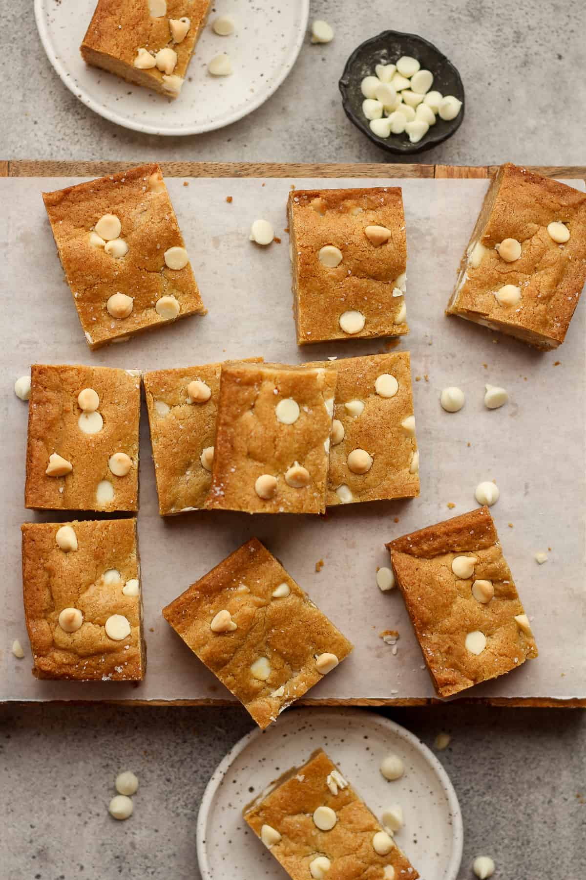 A board with several brown butter blondies, with white chocolate chips.