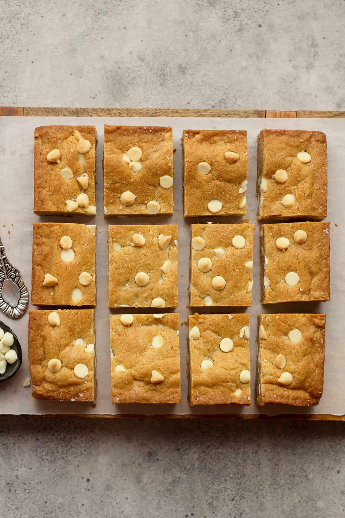 A board with 12 sliced white chocolate blondies.