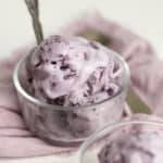 A bowl of melty blueberry ice cream with a purple napkin.