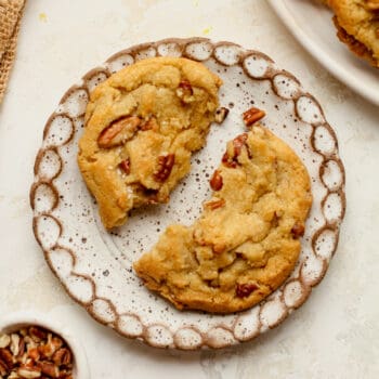A small plate with a halved pecan cookie.