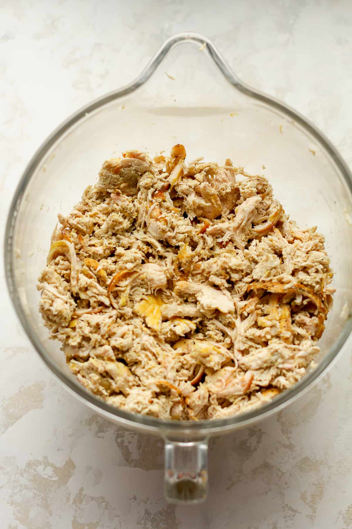 The shredded chicken in a standing mixer bowl.