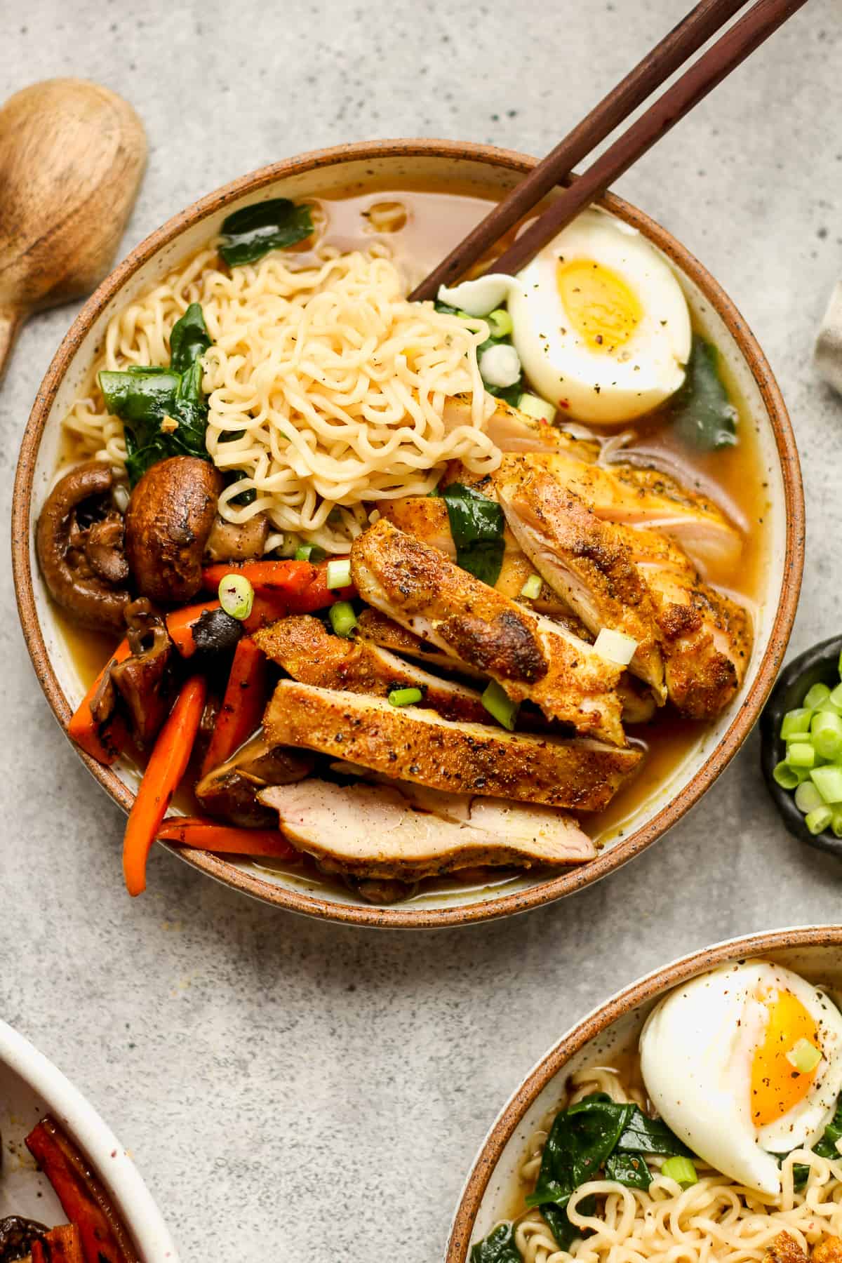 A closeup on a bowl of chicken curry ramen with veggies and a runny egg.