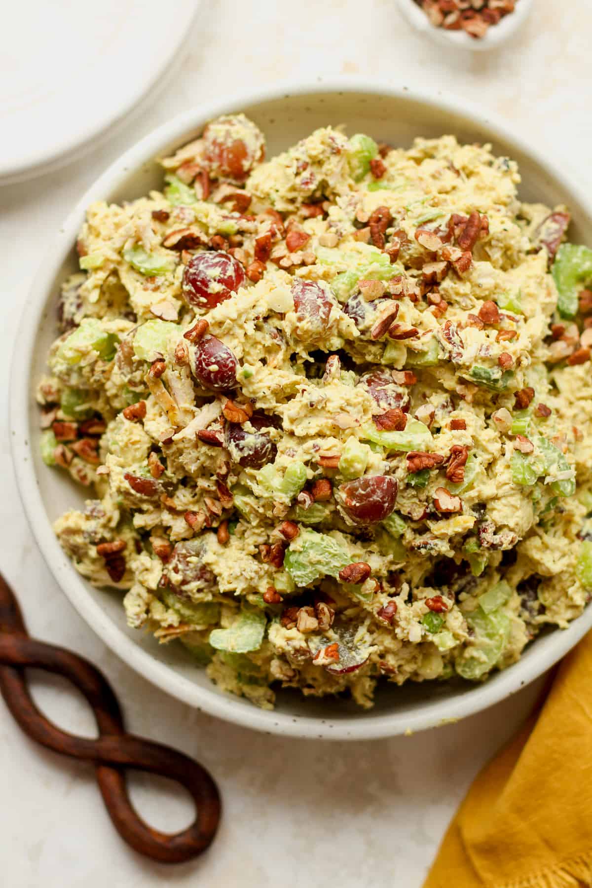 A bowl of chicken salad with grapes, celery, and pecans.