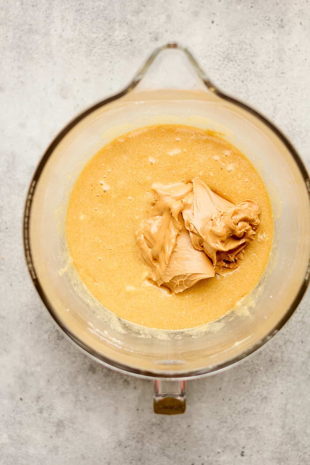 A mixing bowl of the wet ingredients with the peanut butter on top.
