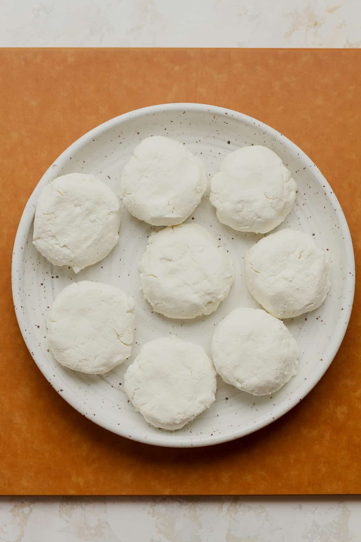 A plate of the rounds of goat cheese before adding the breading.