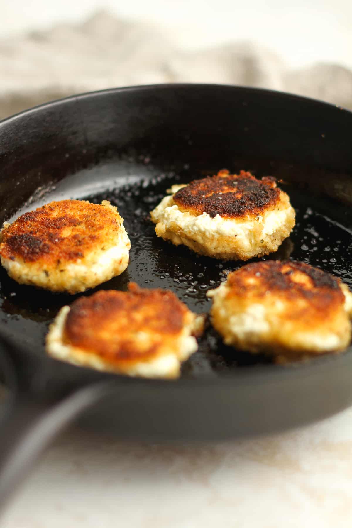 Side view of fried goat cheese in a skillet.