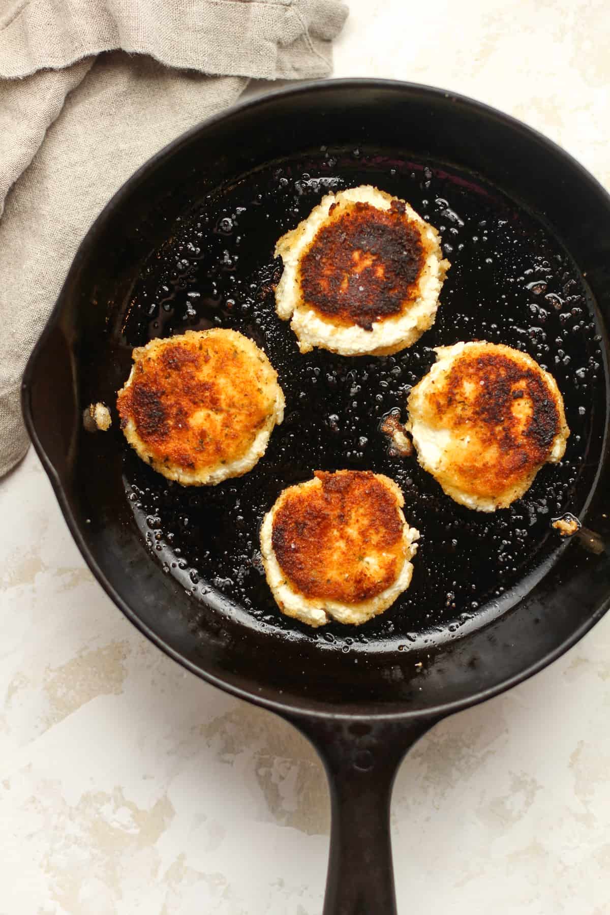 Four rounds of fried goat cheese in a small cast iron skillet.