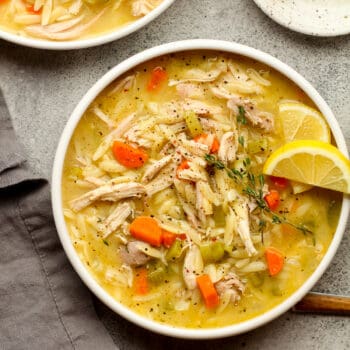 A bowl of chicken orzo soup with lemon.