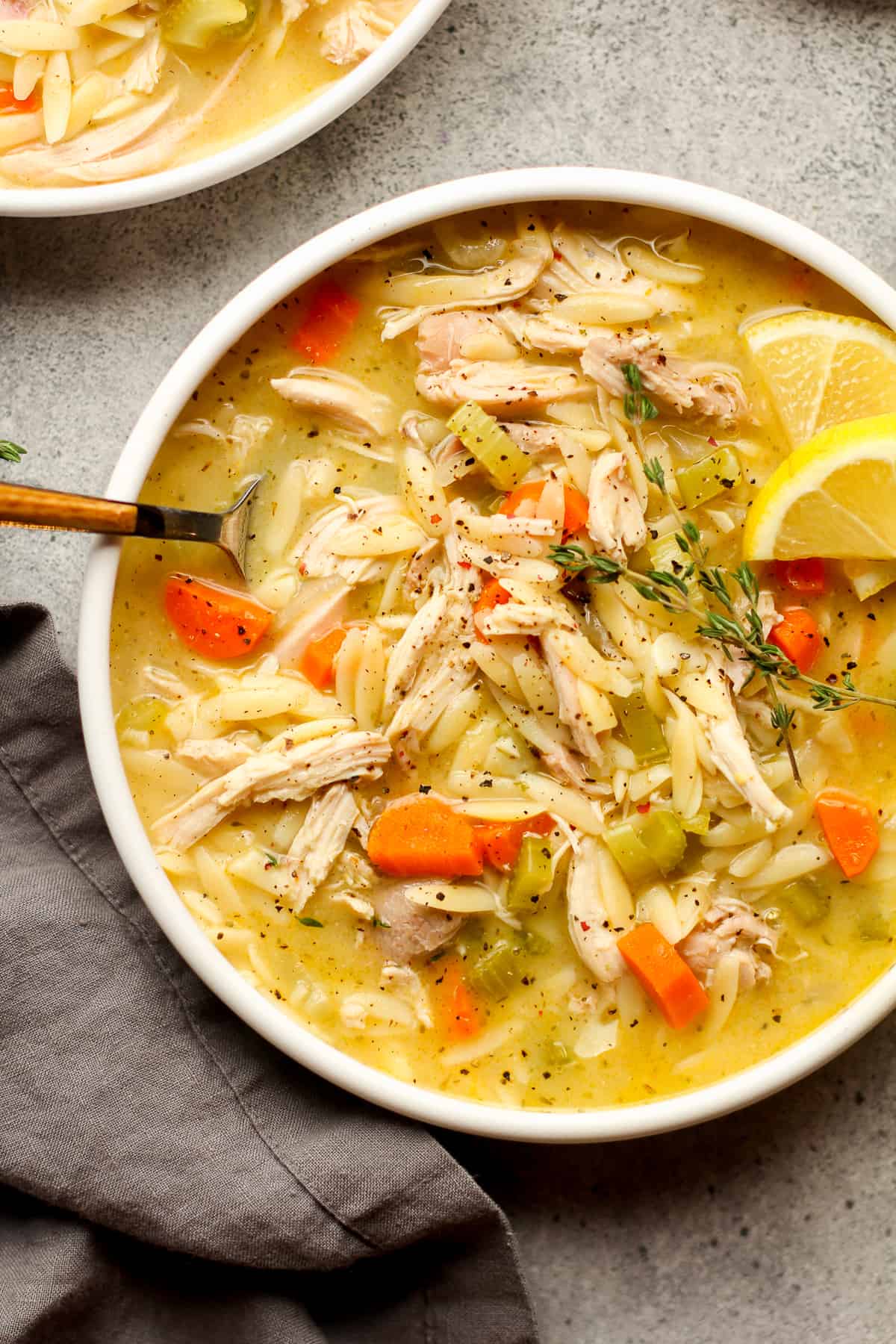 Closeup shot of a bowl of chicken orzo soup with lemon.