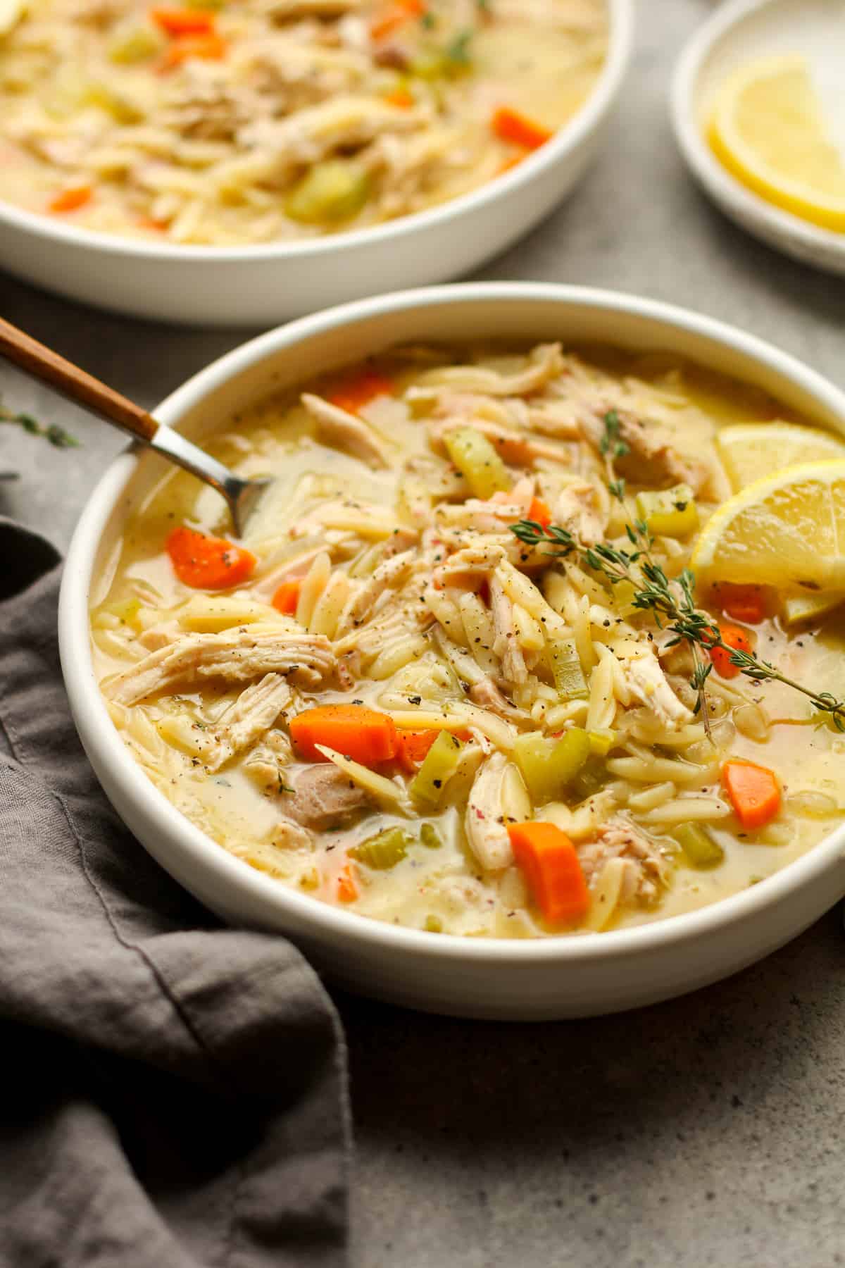 Side view of two bowls of lemon chicken orzo soup.
