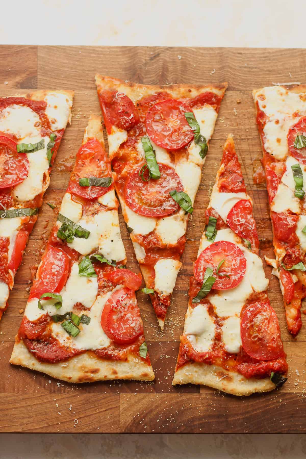 A board of triangular sliced flatbread with tomatoes and fresh mozzarella.