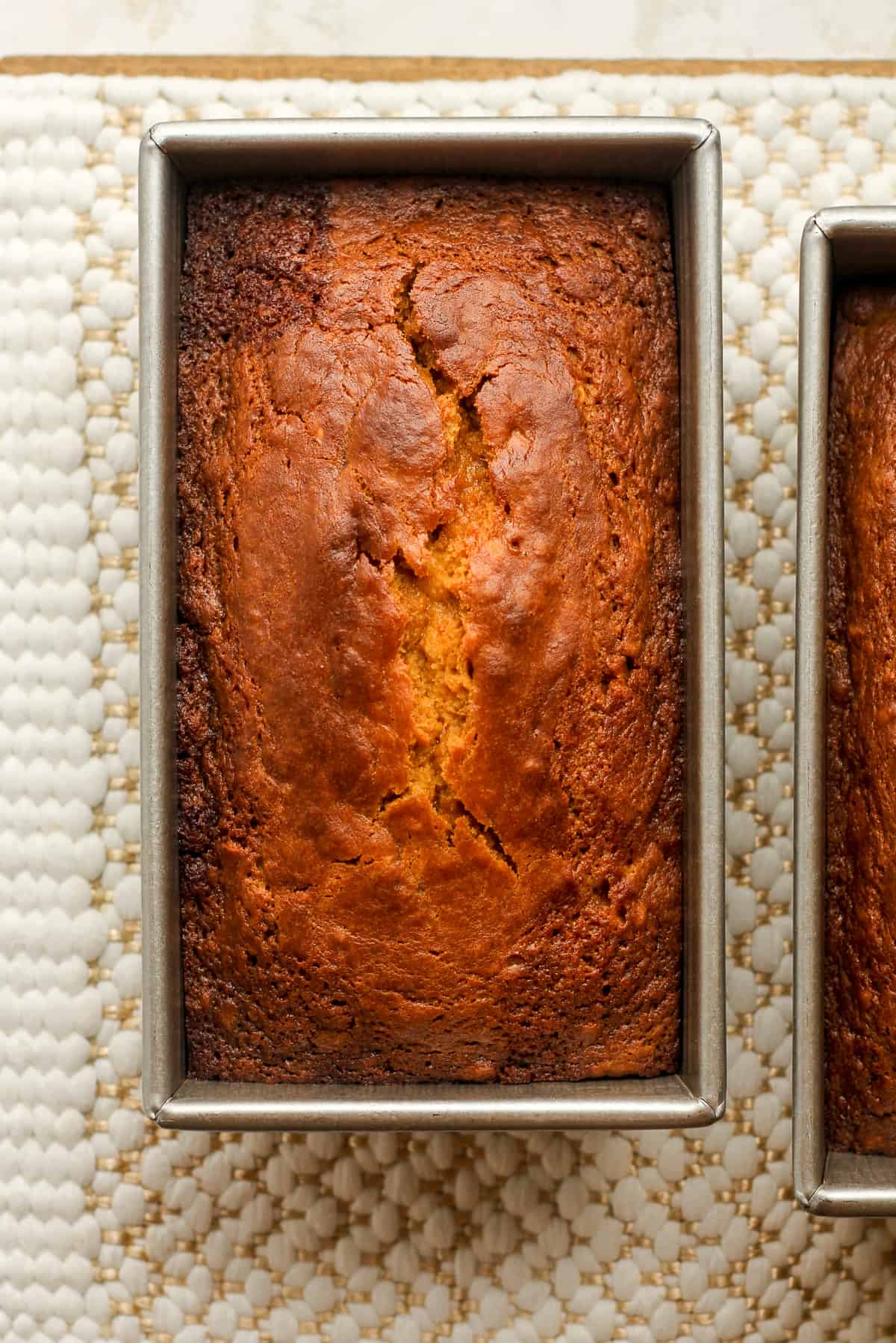 Two baked pumpkin loaves in pans.
