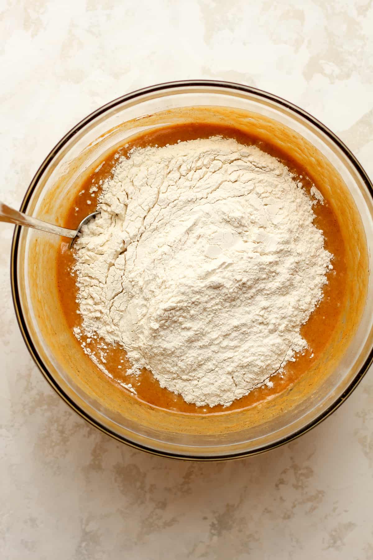 A bowl of the pumpkin batter with flour on top.