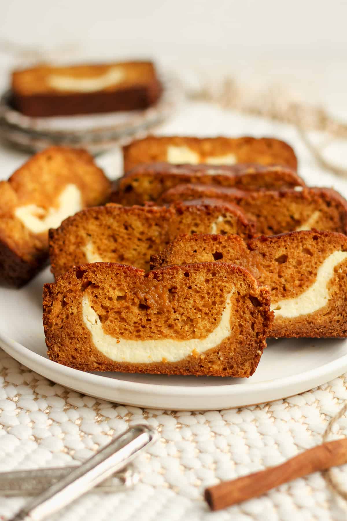 Side view of a plate of sliced pumpkin loaf with cream cheese.