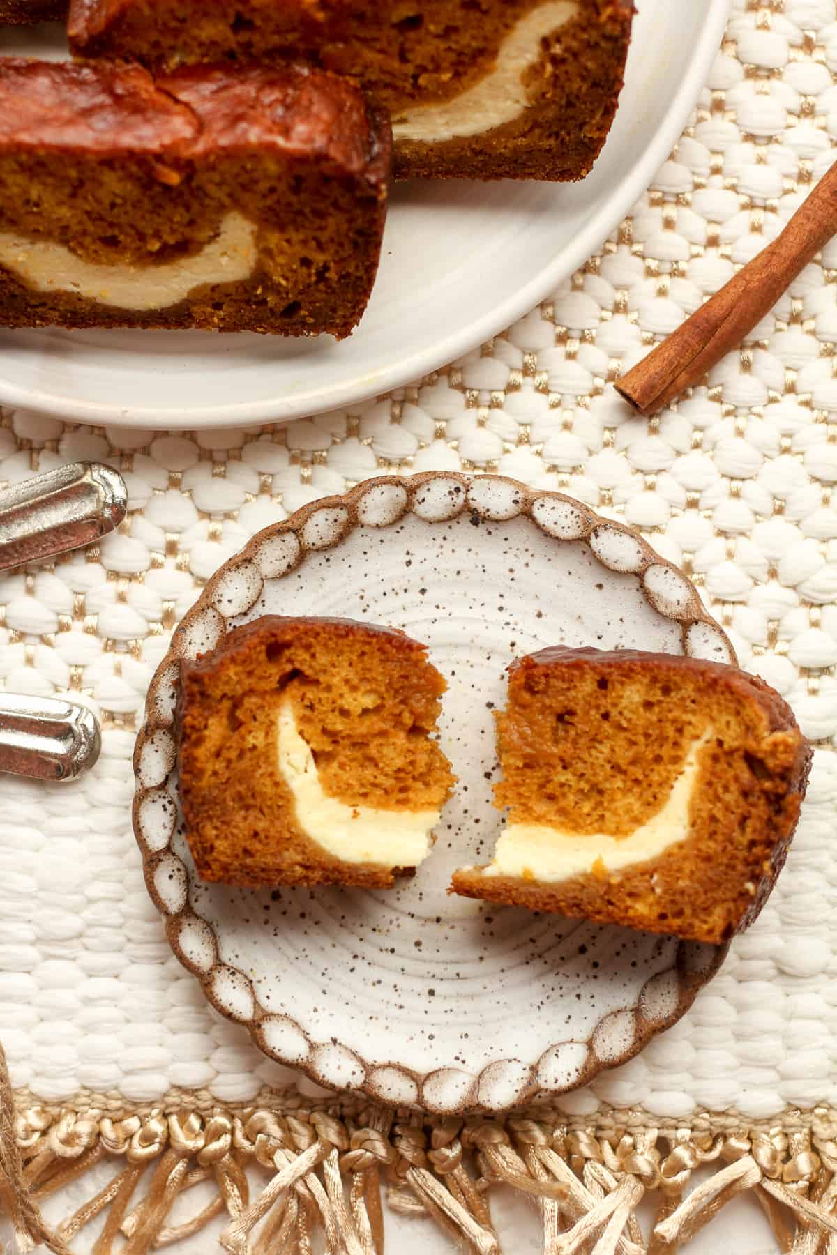 A small plate of a slice of pumpkin loaf split in half.