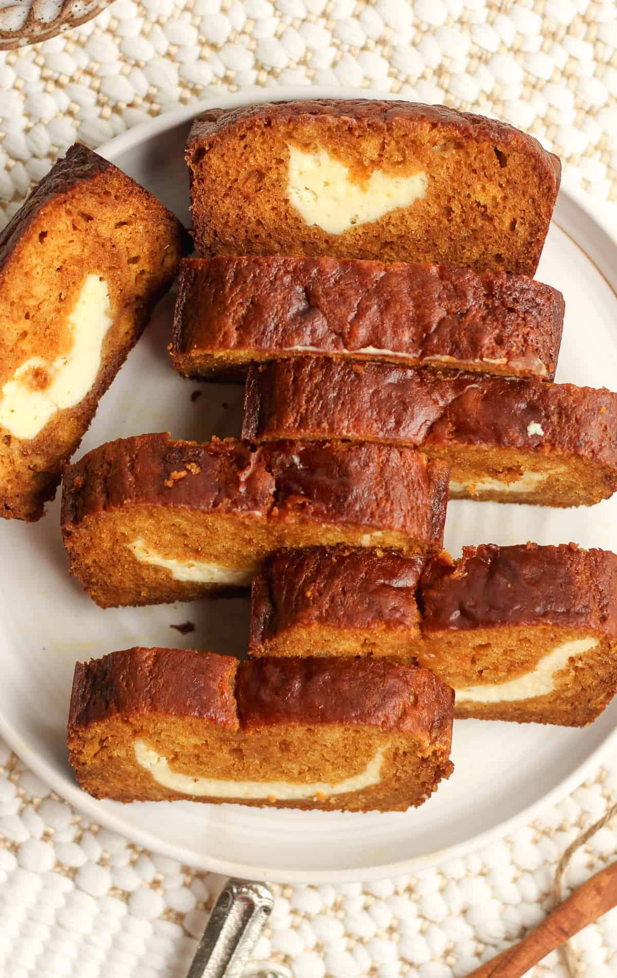 Closeup on a plate of sliced pumpkin loaf with cream cheese filling.