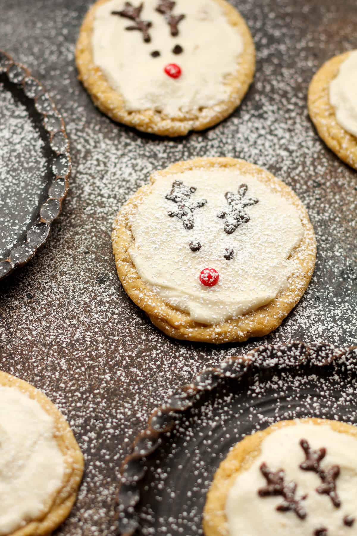 Overhead view of several reindeer sugar cookies with powdered sugar on top.