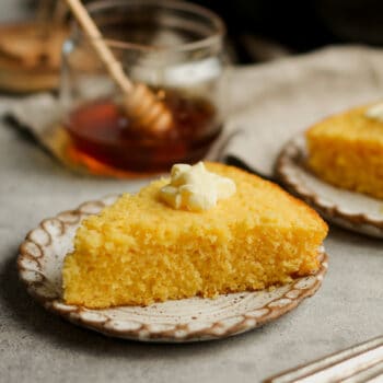 Side view of a slice of sweet cornbread with some butter.