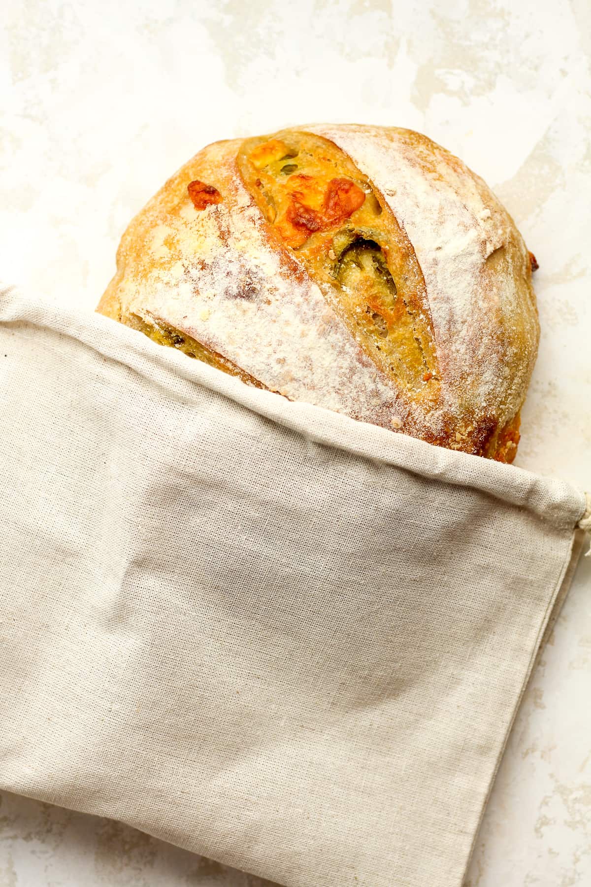 A loaf of sourdough bread in a linen bag.