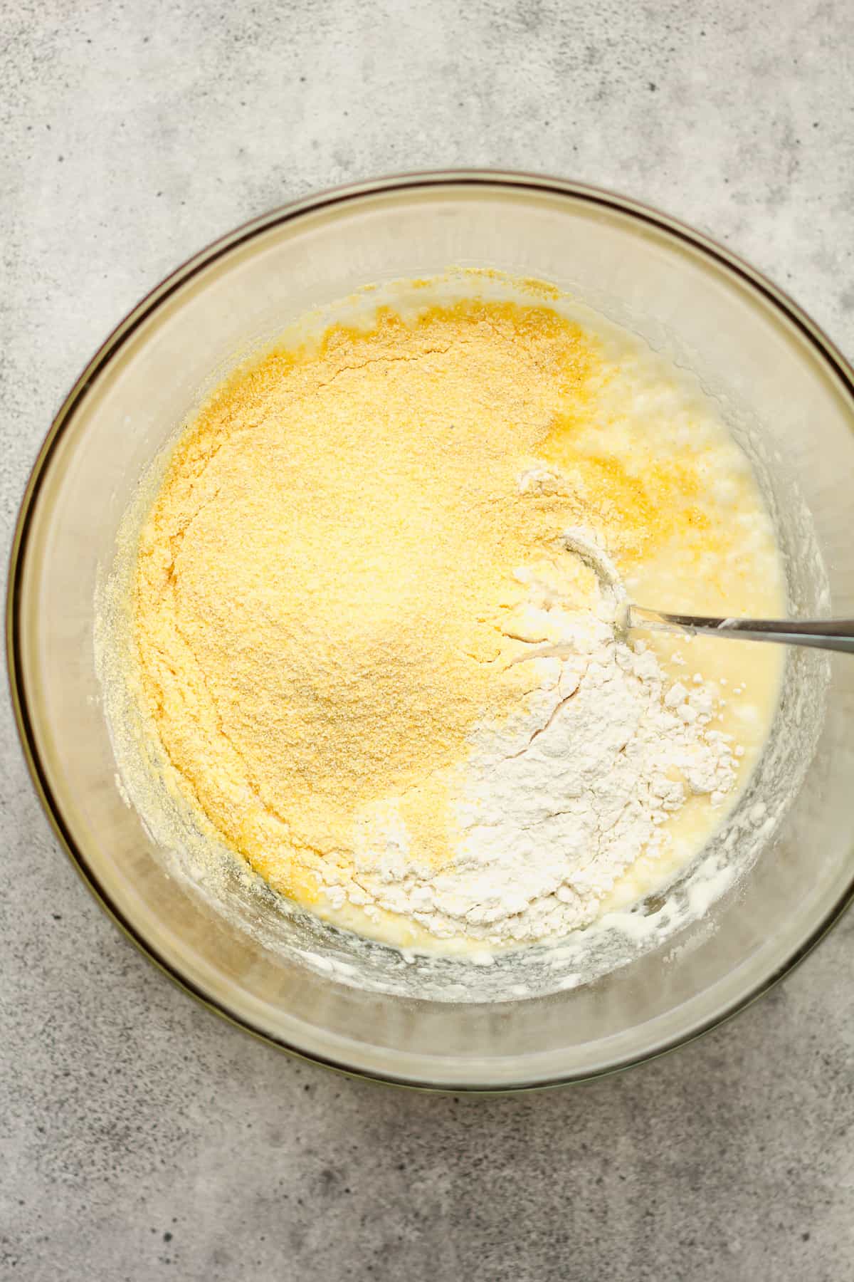 A bowl of the cornbread batter with the flour and cornmeal on top.