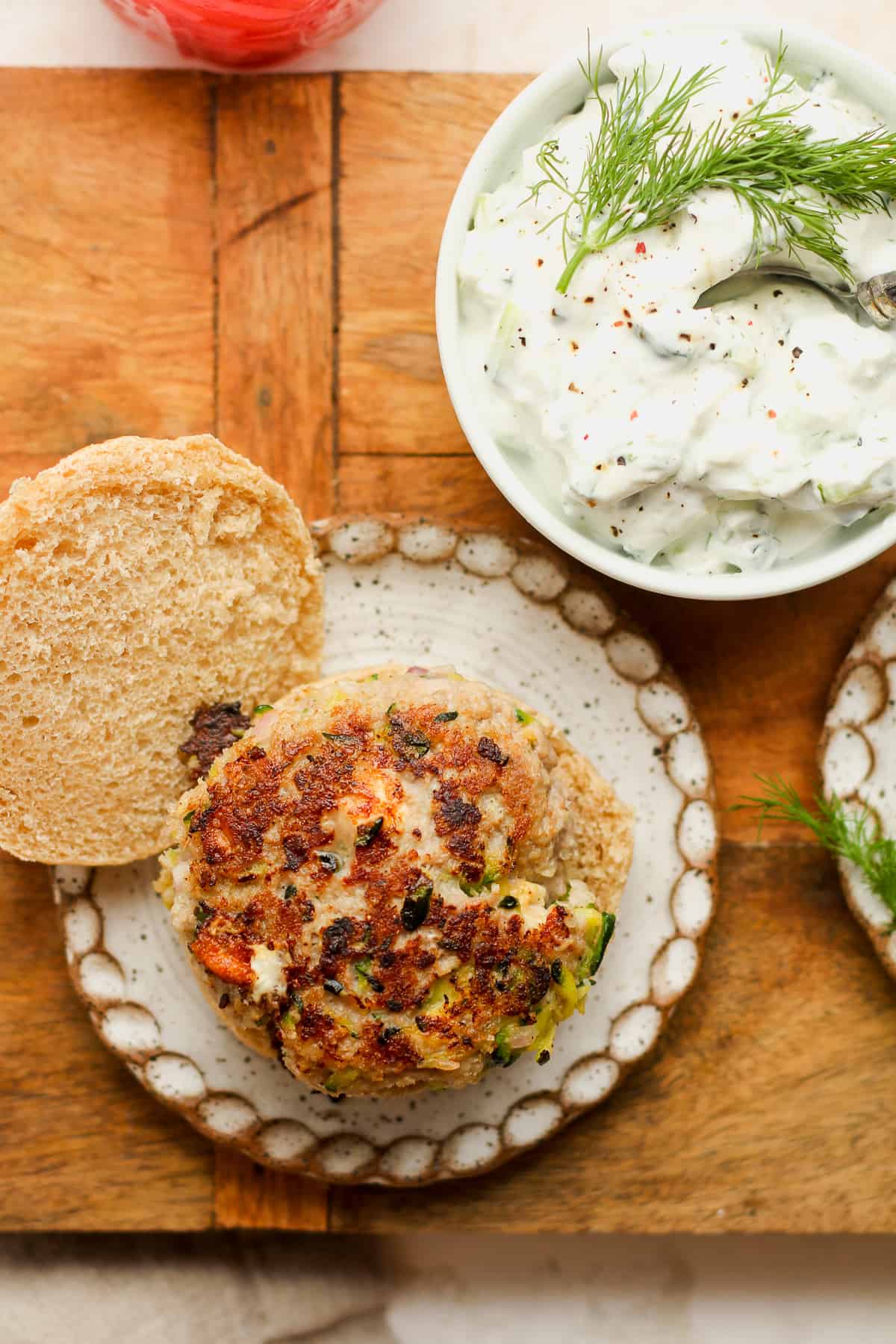 Overhead view of a turkey burger with a bowl of tzatziki sauce.