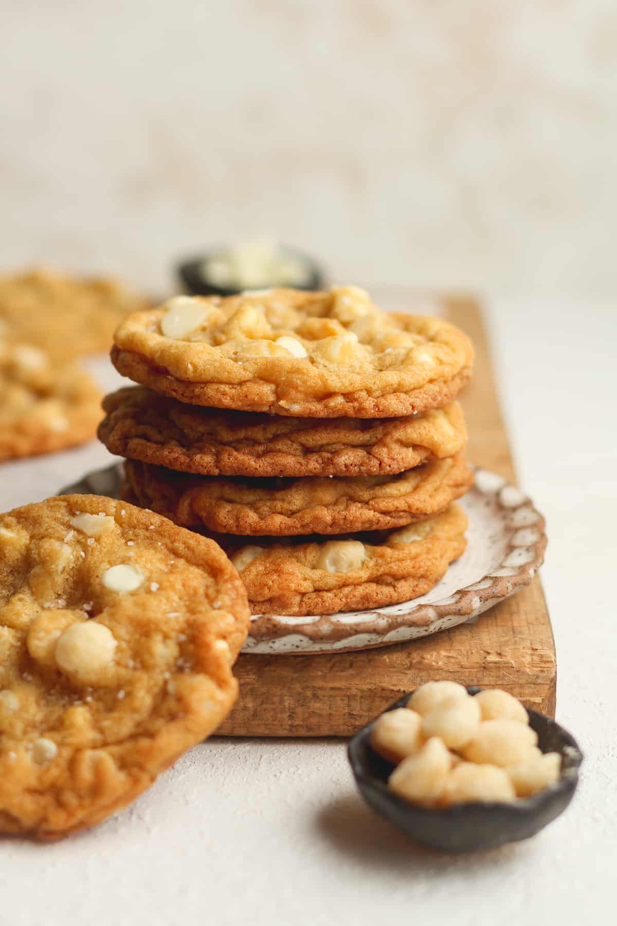 A small plate of four stacked white chocolate cookies with macadamia nuts.