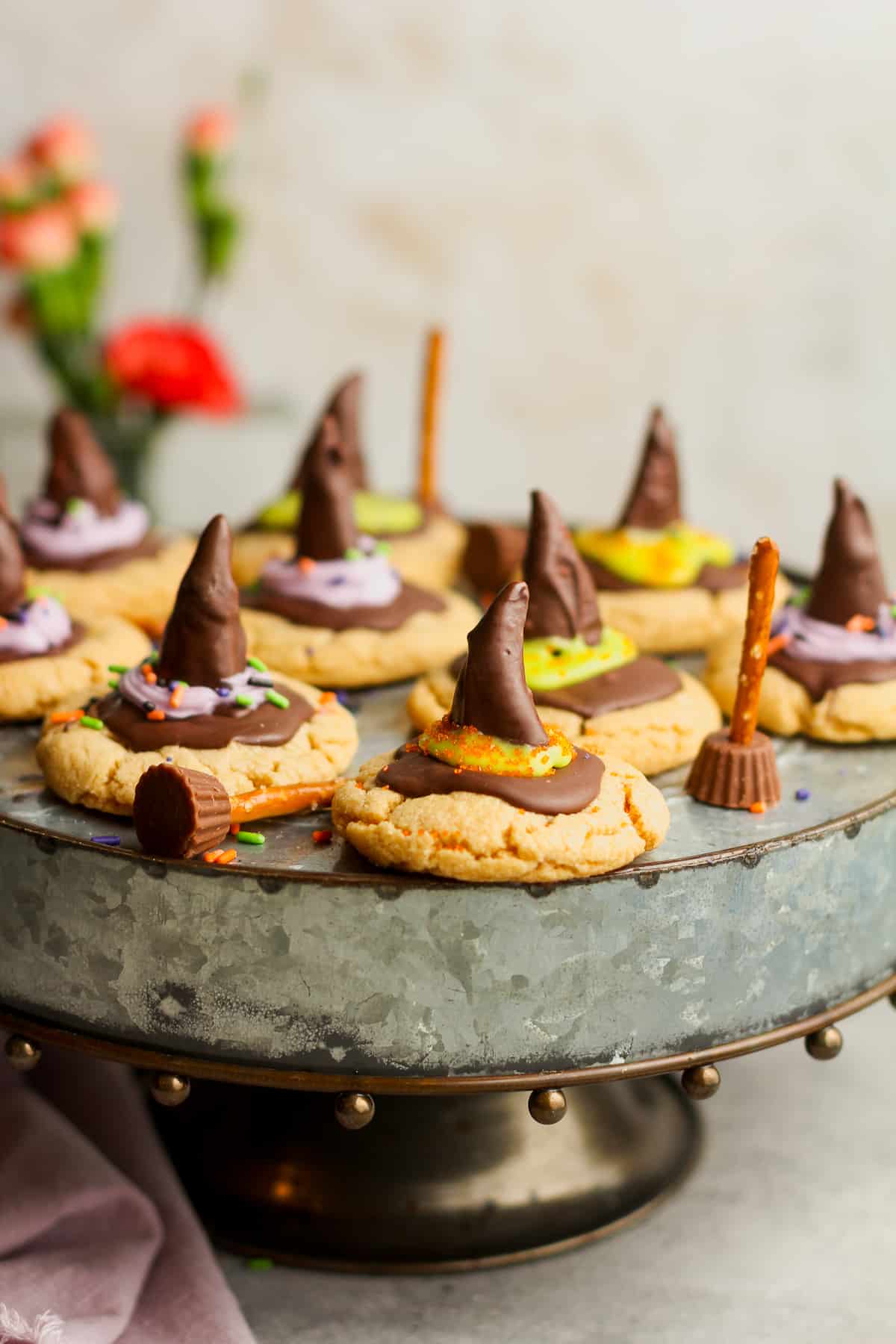 A silver cake plate of witch hat peanut butter cookies with broomsticks.