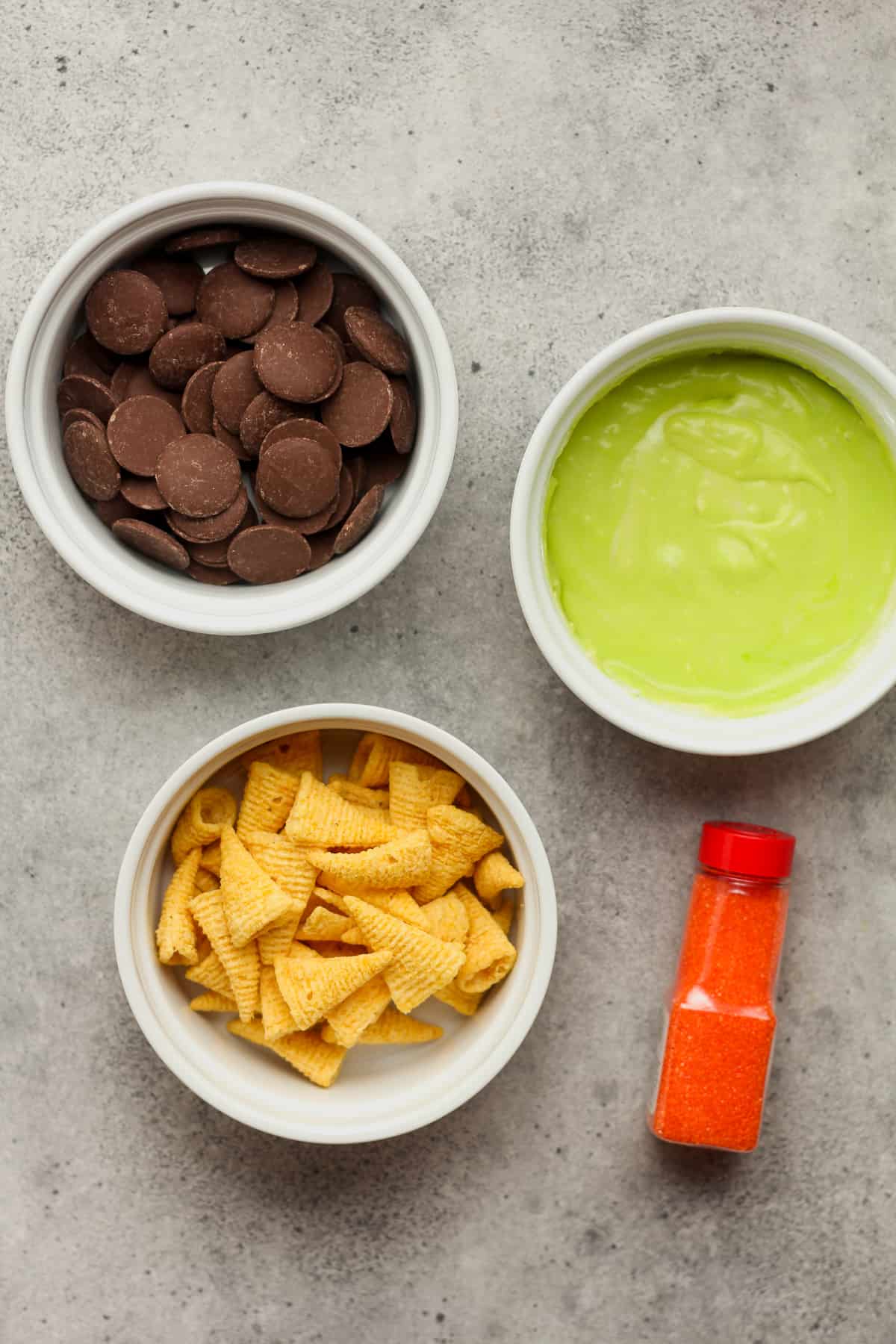 Bowls of the chocolate, bugles, green frosting, and orange sprinkles.