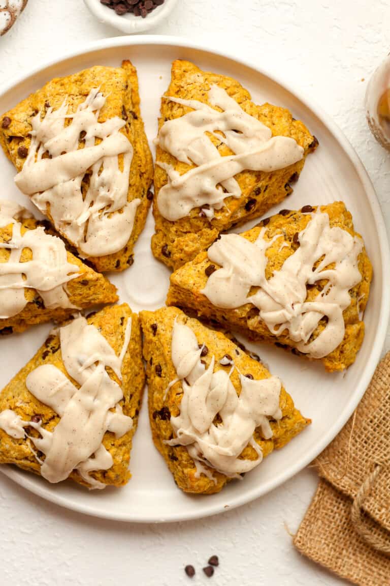 A white plate of iced pumpkin scones.